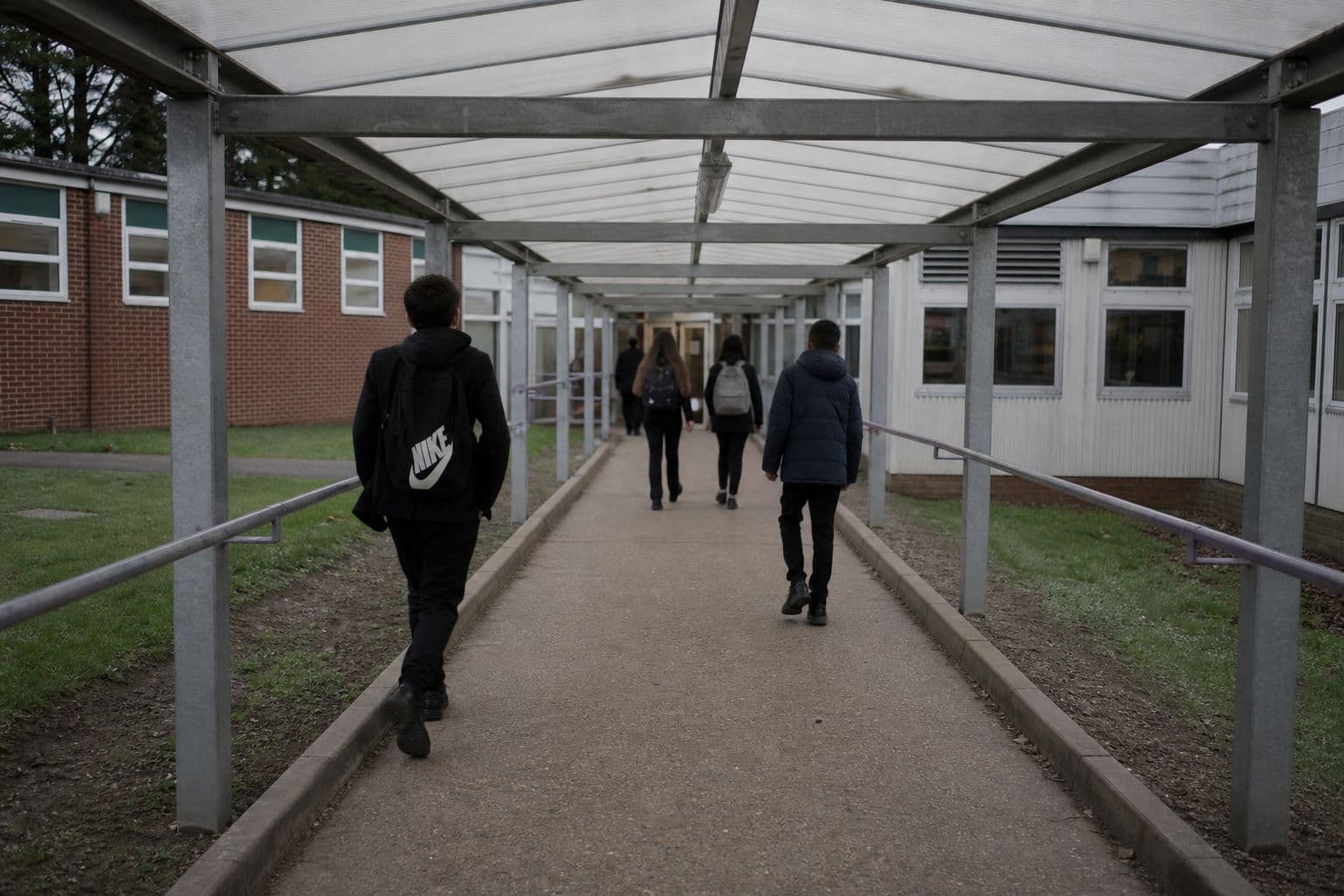 Pupils walking along a long covered walkway between school buildings