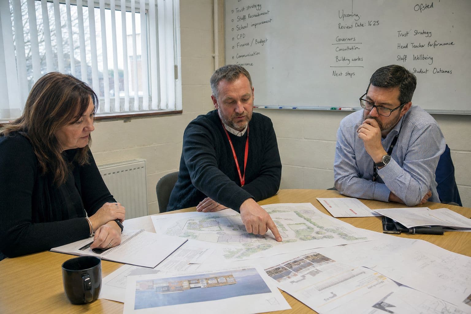 Three colleagues reviewing site plans together at a table