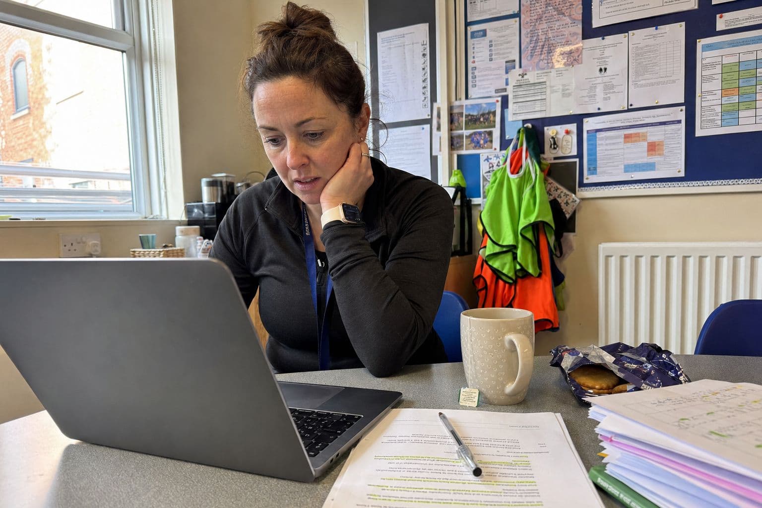 Teacher working on a grant application on a laptop in a school office