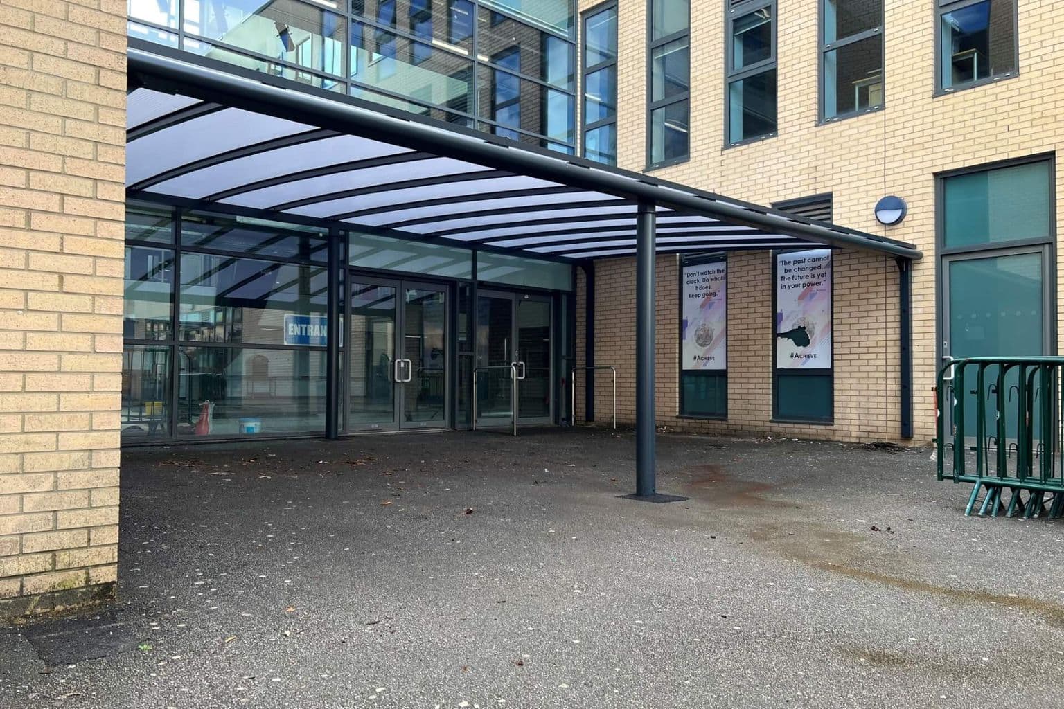 Aluminium canopy with a glazed roof over the paved forecourt of a building entrance