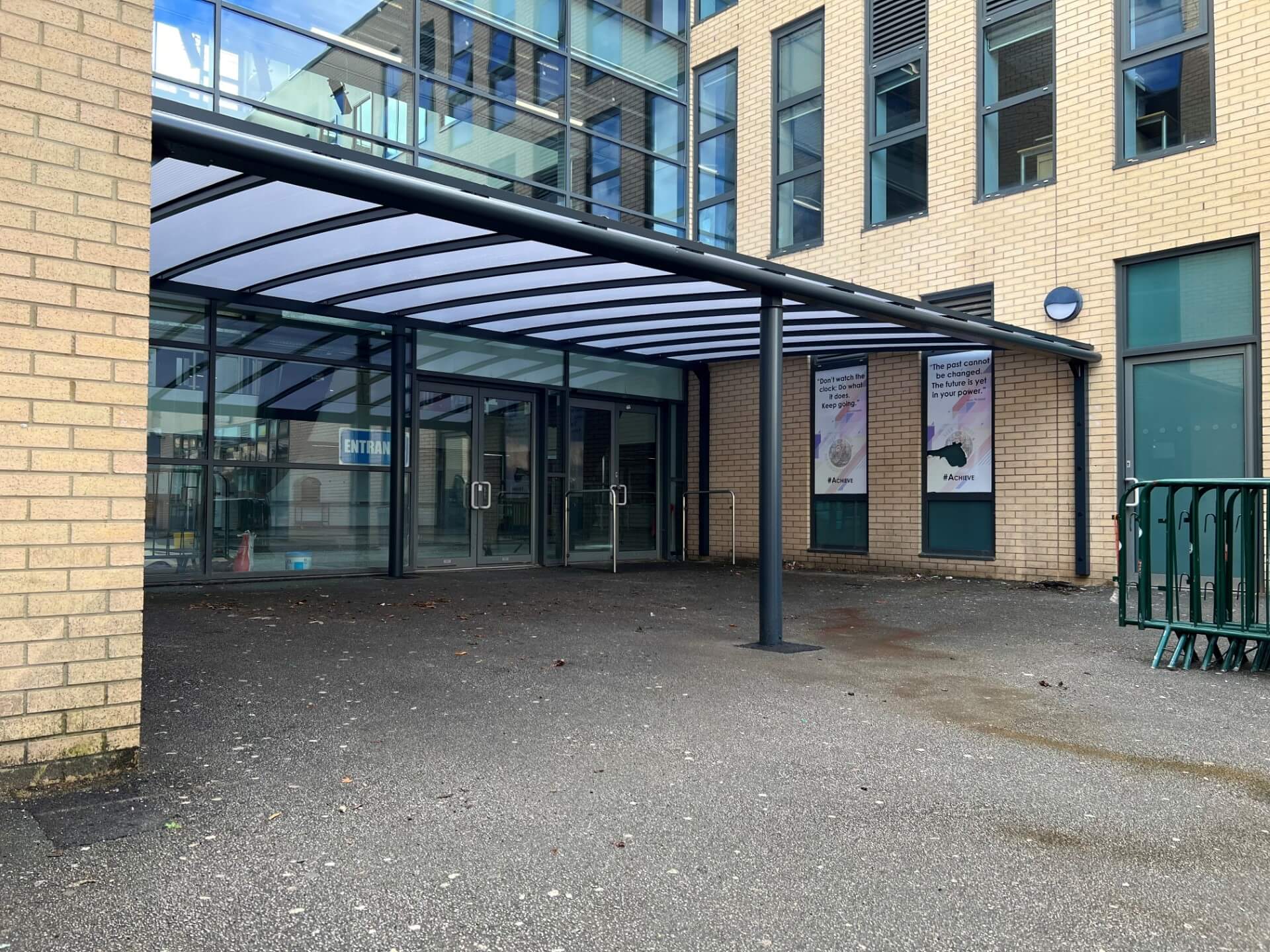Grey column-supported entrance canopy over a glazed building entrance
