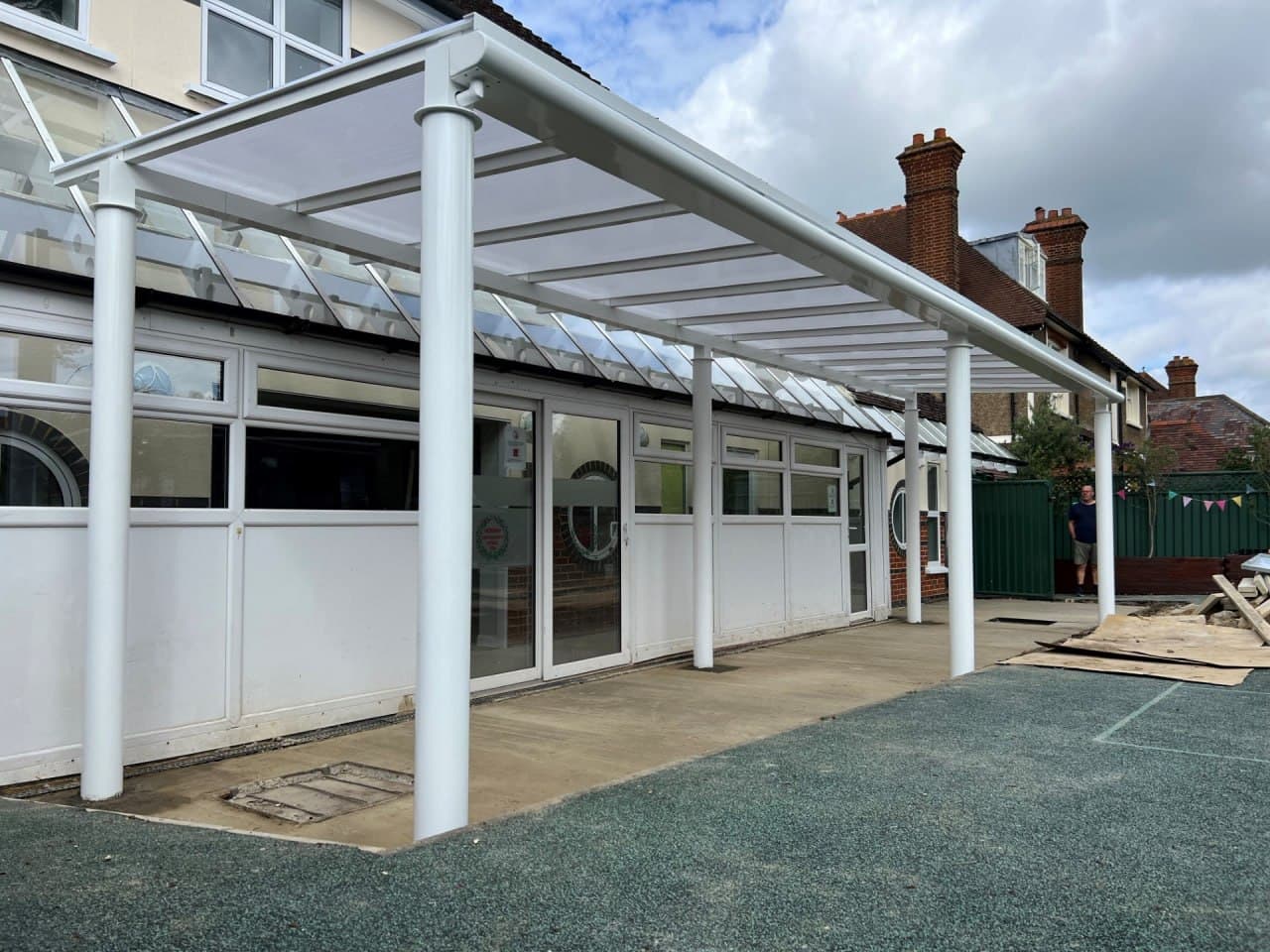 White aluminium canopy with flat polycarbonate roof at Victorian primary school building, clean modern installation