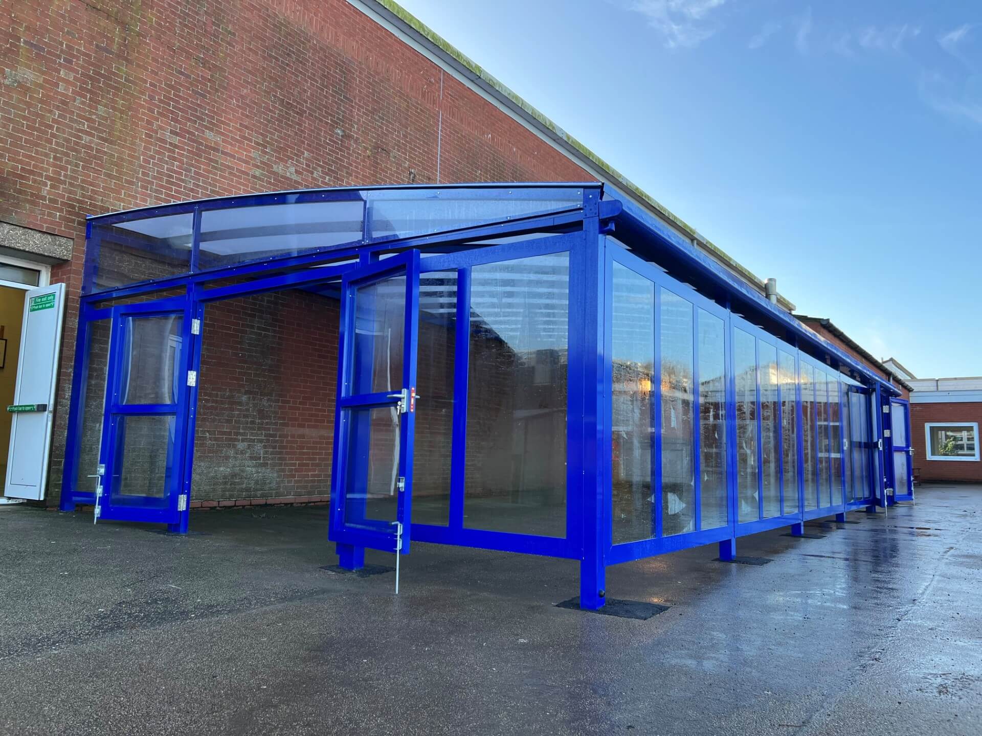 Blue-framed glazed sunlight room along the side of a school building
